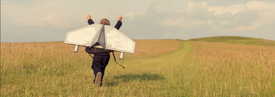 Person runs over a meadow and has a self-built flying machine on his back.